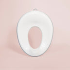 Toalettsits för barn i vit plast med silikongrepp och stänkskydd.